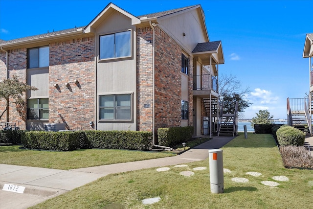 view of side of property with a yard, stairway, and brick siding