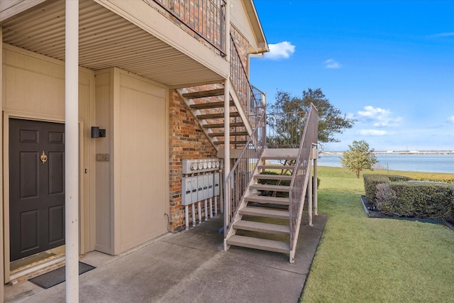 view of exterior entry featuring a water view and a yard