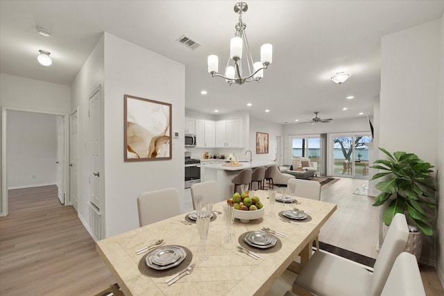 dining space featuring light wood finished floors, ceiling fan with notable chandelier, visible vents, and recessed lighting