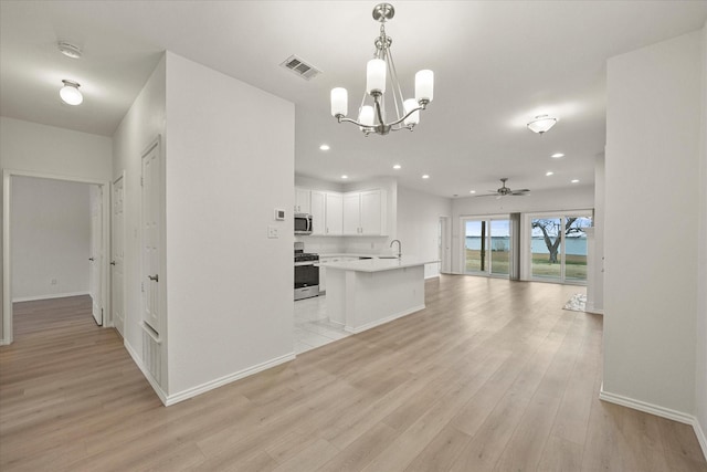 kitchen with stainless steel appliances, visible vents, open floor plan, white cabinetry, and light wood-type flooring