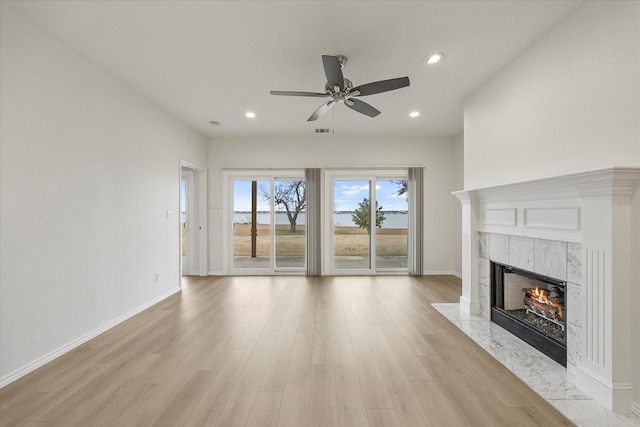 unfurnished living room with light wood-style flooring, a fireplace, baseboards, and recessed lighting