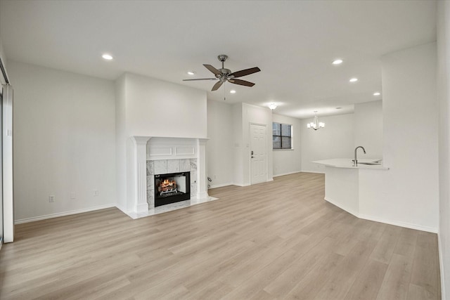 unfurnished living room featuring a premium fireplace, a sink, light wood-style flooring, and recessed lighting