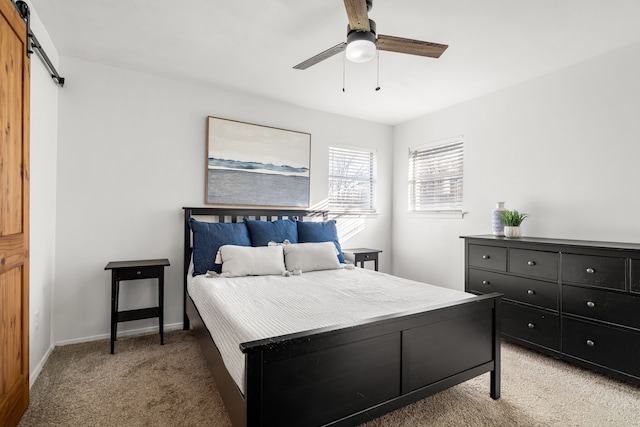 bedroom featuring a barn door, baseboards, ceiling fan, and light colored carpet