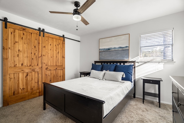 bedroom featuring light carpet, a barn door, baseboards, and a ceiling fan