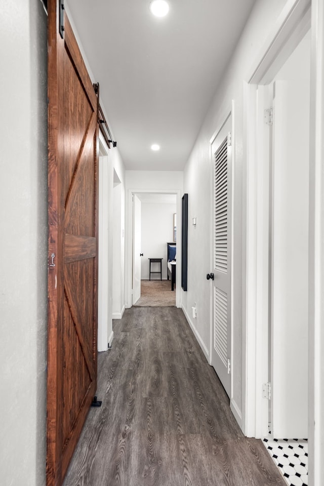 hall with dark wood-style floors, a barn door, recessed lighting, and baseboards