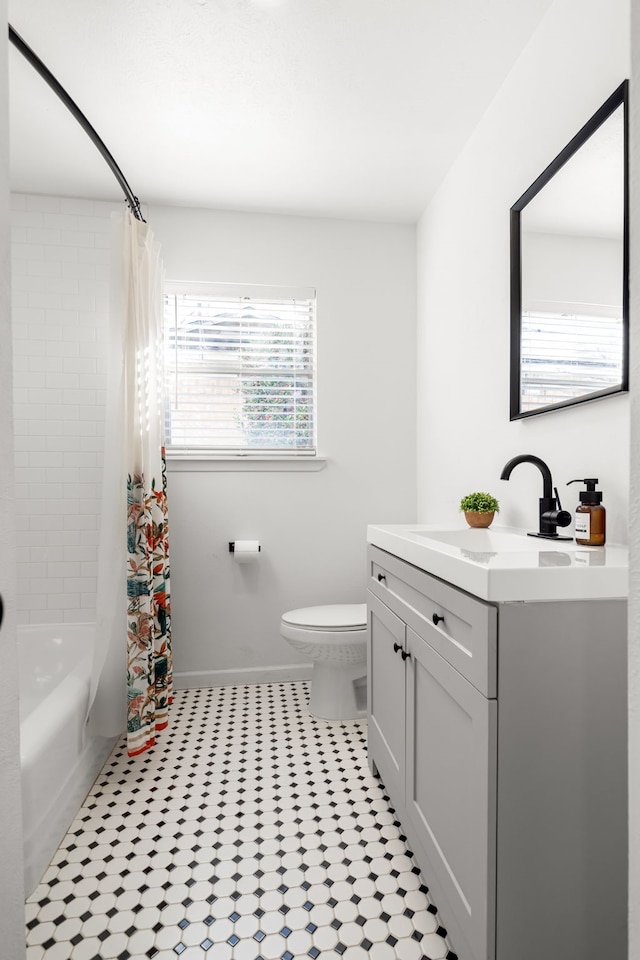 bathroom featuring shower / bath combo with shower curtain, vanity, toilet, and baseboards