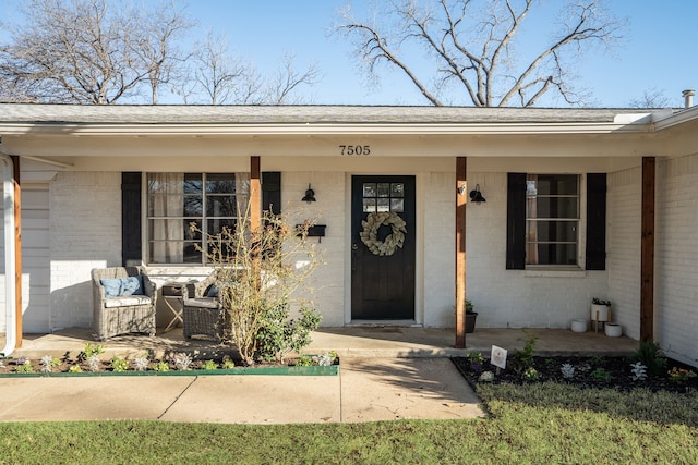 doorway to property with a porch and brick siding