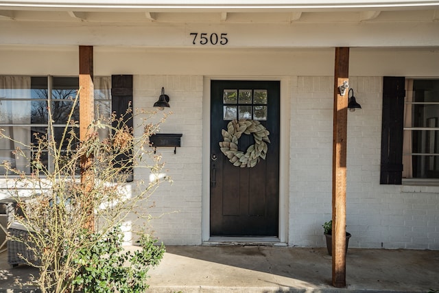 property entrance featuring a porch and brick siding