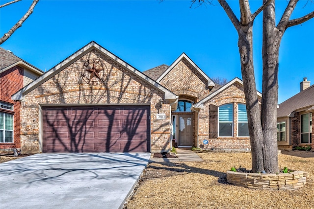 french country style house with a garage, driveway, and brick siding