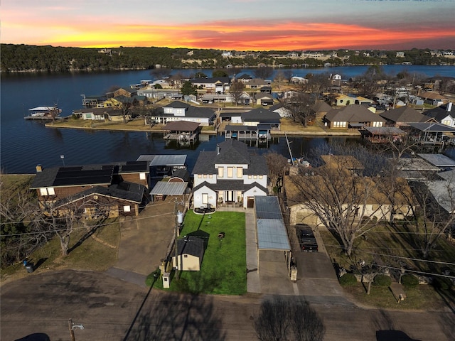 aerial view at dusk with a residential view and a water view