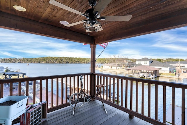 wooden deck with a water view and ceiling fan