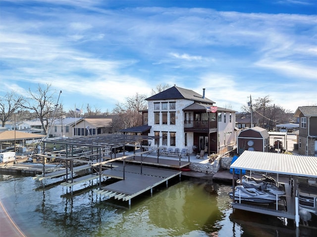 view of dock featuring a balcony, boat lift, and a residential view