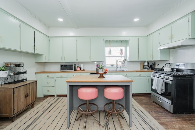 kitchen featuring dark wood-style flooring, appliances with stainless steel finishes, a sink, a kitchen island, and under cabinet range hood