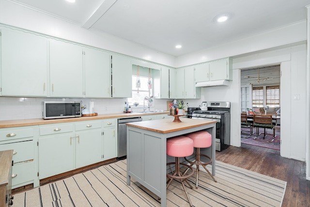 kitchen featuring light wood finished floors, appliances with stainless steel finishes, a healthy amount of sunlight, and under cabinet range hood