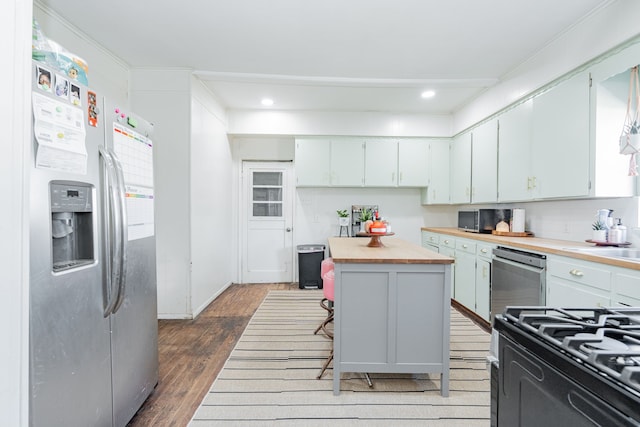 kitchen with stainless steel appliances, wood finished floors, wood counters, a center island, and a kitchen bar