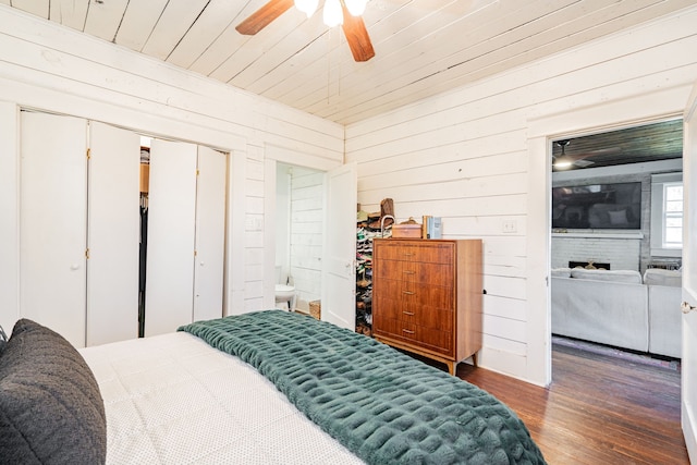 bedroom with wooden walls, a fireplace, wood finished floors, a ceiling fan, and wood ceiling