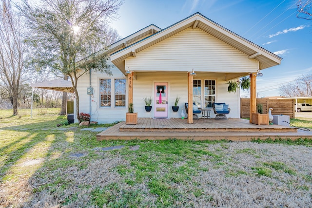 rear view of house featuring covered porch and a lawn