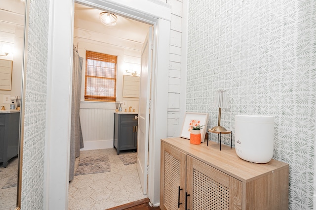 bathroom featuring baseboards, vanity, and wallpapered walls