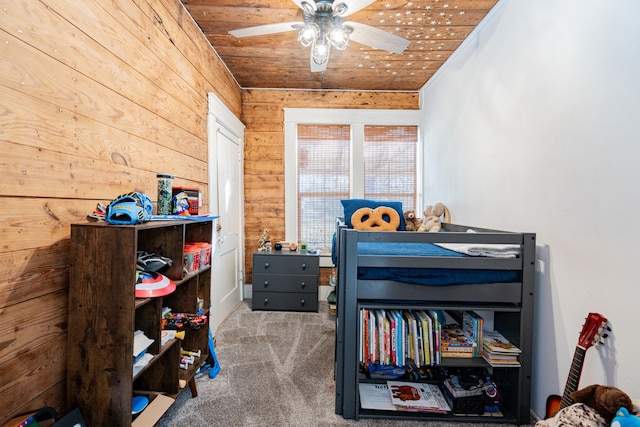 carpeted bedroom with wooden ceiling, ceiling fan, and wood walls