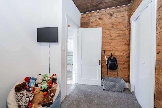 hallway featuring carpet floors, wooden ceiling, and wood walls