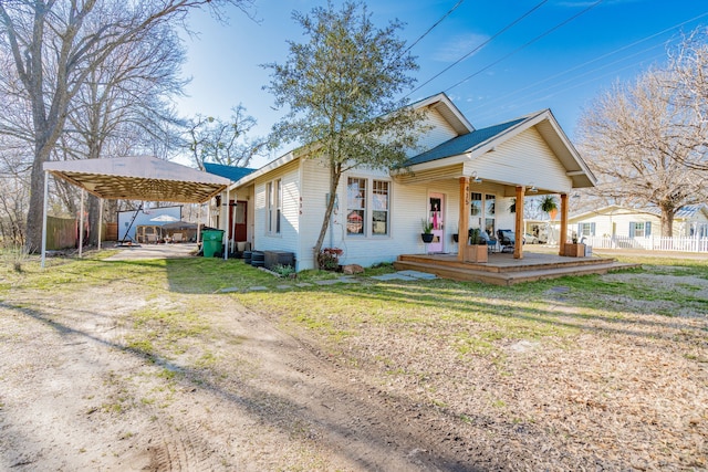 view of front of property with dirt driveway, a carport, a front yard, and fence