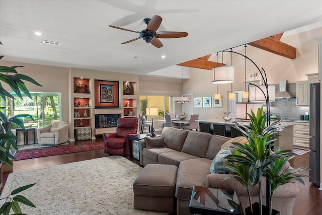 living room with a healthy amount of sunlight, ceiling fan, visible vents, and dark wood-type flooring