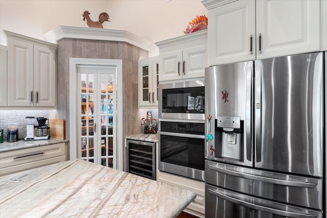 kitchen featuring white cabinets, beverage cooler, stainless steel appliances, backsplash, and glass insert cabinets