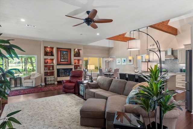 living room with dark wood finished floors, a towering ceiling, visible vents, recessed lighting, and a ceiling fan