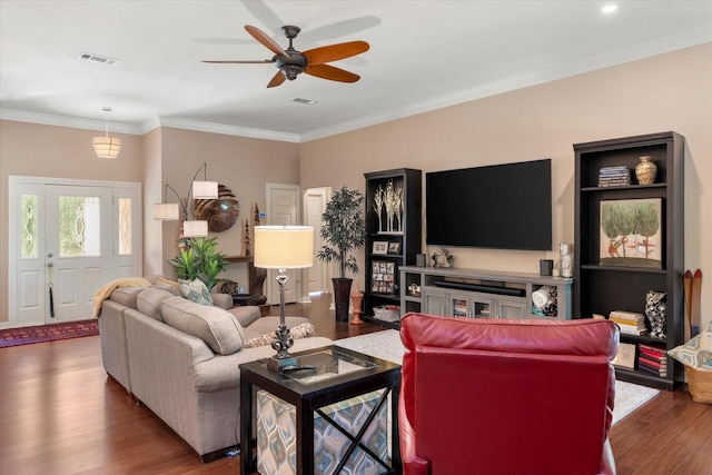 living room featuring wood finished floors, visible vents, ceiling fan, and crown molding