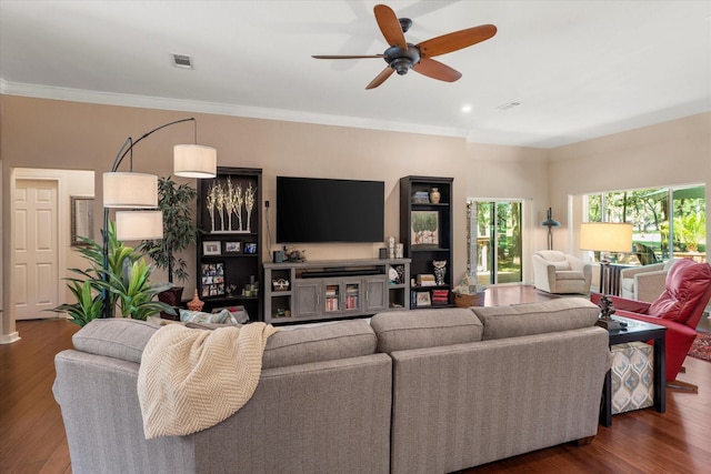 living room with visible vents, a ceiling fan, wood finished floors, and ornamental molding