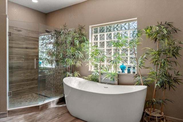 bathroom featuring a stall shower, a soaking tub, and wood finished floors