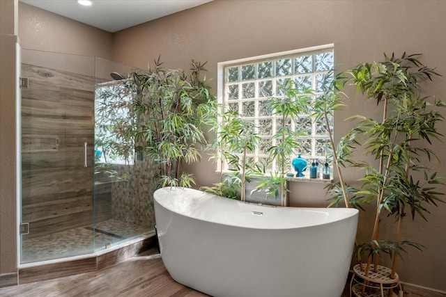 bathroom featuring a shower stall, a soaking tub, and wood finished floors