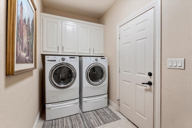 clothes washing area with cabinet space, independent washer and dryer, baseboards, and light tile patterned floors