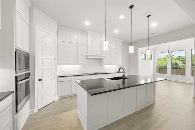 4814 Nomad Dr, Midlothian, TX 76065 - kitchen featuring stainless steel appliances, a sink, dark countertops, light wood-style flooring, and white cabinets