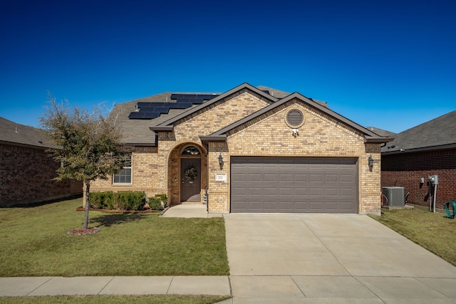 view of front of property featuring driveway, a garage, a front yard, roof mounted solar panels, and brick siding