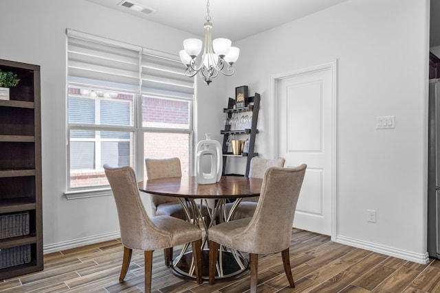 dining room with a chandelier, visible vents, baseboards, and wood finished floors