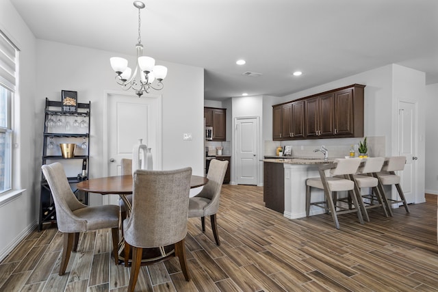 dining room with a chandelier, recessed lighting, wood finish floors, visible vents, and baseboards