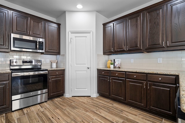 kitchen featuring tasteful backsplash, dark brown cabinetry, light wood-style flooring, and stainless steel appliances