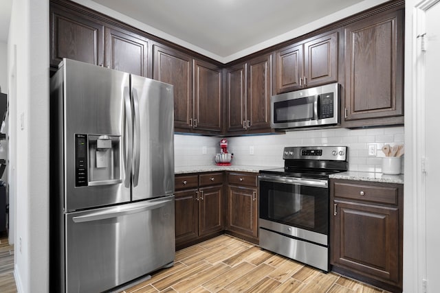 kitchen with stainless steel appliances, wood finish floors, dark brown cabinetry, and tasteful backsplash