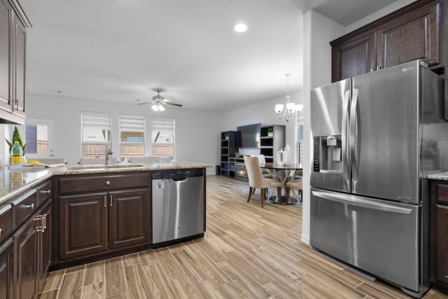 kitchen featuring light wood-type flooring, dark brown cabinetry, stainless steel appliances, and a sink