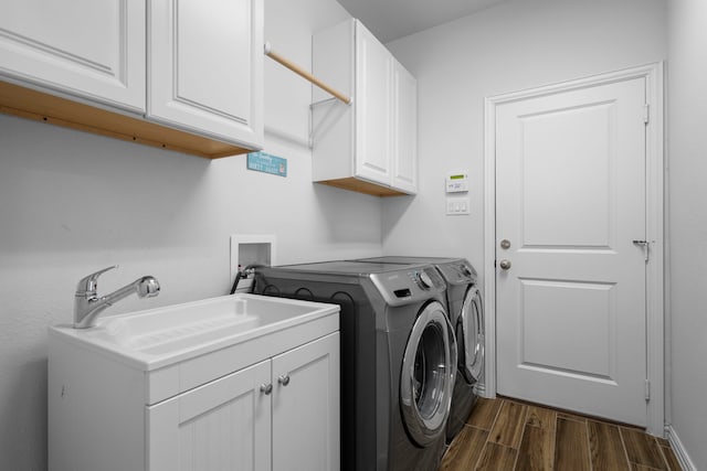 washroom featuring a sink, cabinet space, washer and clothes dryer, and dark wood finished floors