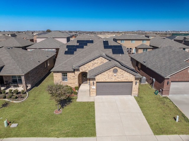 view of front of house featuring brick siding, concrete driveway, a garage, a residential view, and a front lawn