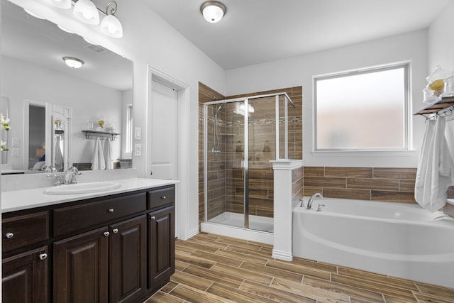 ensuite bathroom with a stall shower, connected bathroom, vanity, wood finish floors, and a bath