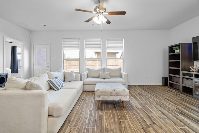 living area with a ceiling fan, visible vents, baseboards, and wood finished floors