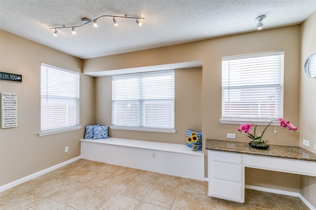 unfurnished room featuring light tile patterned flooring, a textured ceiling, and baseboards