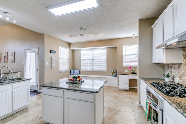 kitchen with backsplash, a kitchen island, a sink, black gas stovetop, and oven