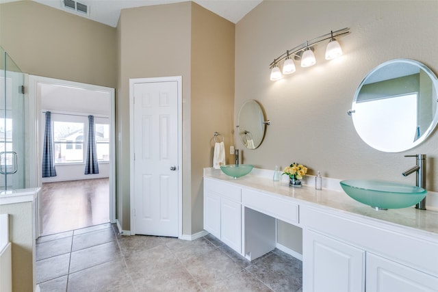 bathroom featuring visible vents, a sink, a shower stall, and double vanity