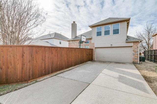 exterior space with central air condition unit, driveway, a garage, and fence