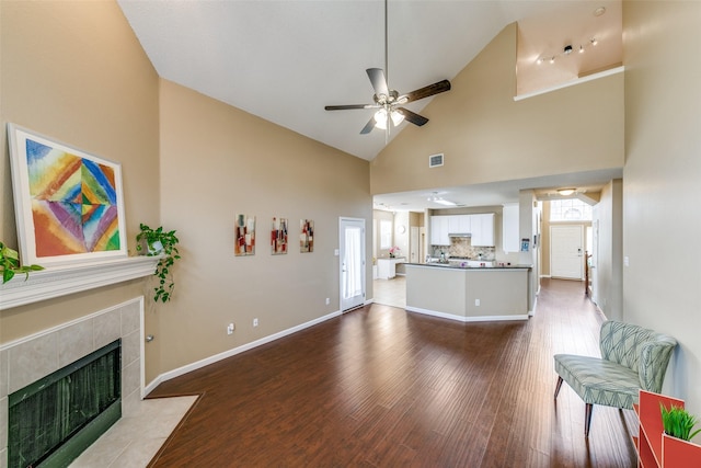 living area featuring a healthy amount of sunlight, ceiling fan, a tiled fireplace, and wood finished floors