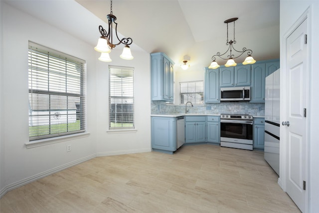 kitchen featuring decorative backsplash, appliances with stainless steel finishes, light countertops, blue cabinetry, and a sink